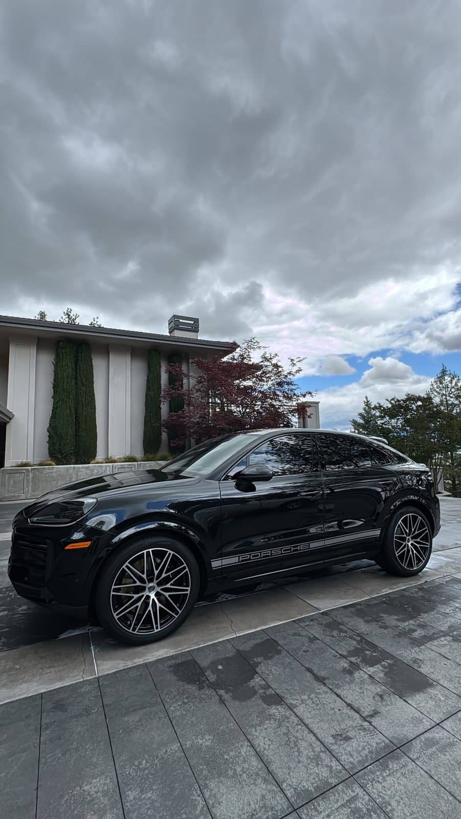 Black SUV detailed in a residential driveway under an overcast sky.